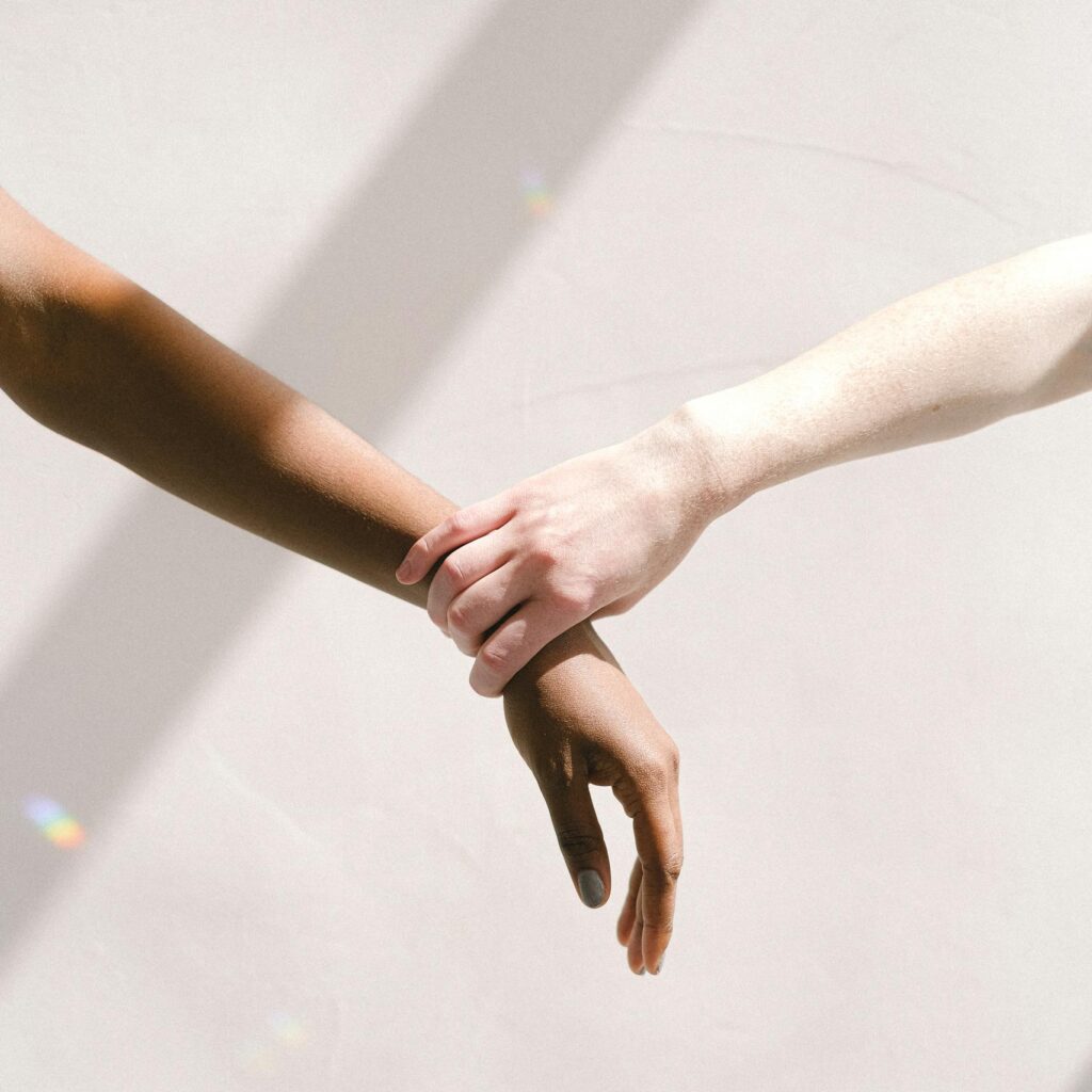 Two people of different ethnic backgrounds holding hands, symbolizing unity and support.